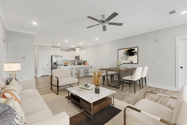 living room featuring light hardwood / wood-style floors, ceiling fan, and crown molding