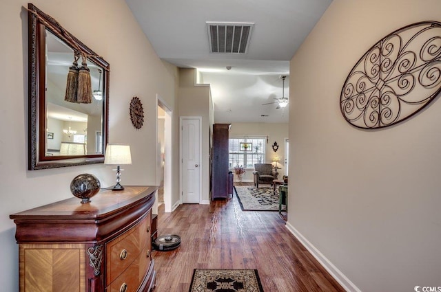 hall featuring an inviting chandelier and dark wood-type flooring