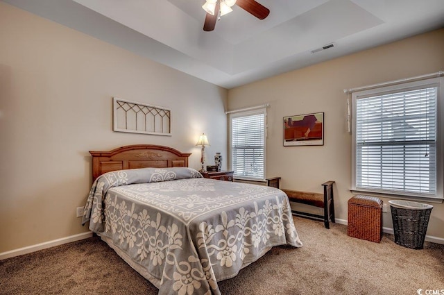 bedroom with a raised ceiling, ceiling fan, and light carpet