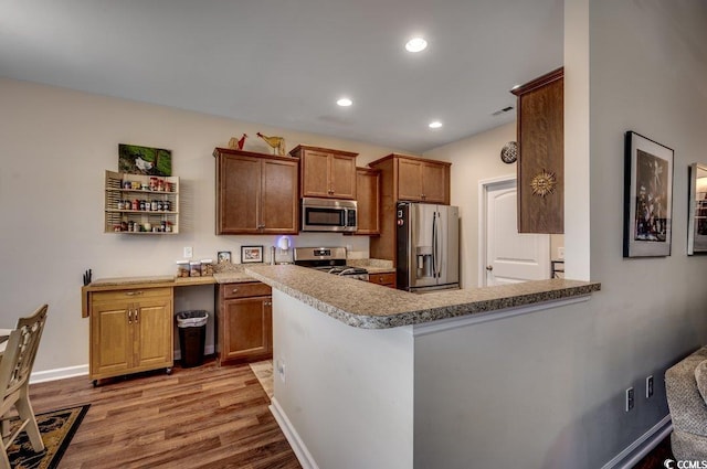 kitchen with kitchen peninsula, appliances with stainless steel finishes, and light hardwood / wood-style flooring