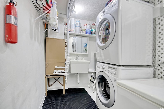 washroom featuring stacked washer and dryer, a textured ceiling, and sink