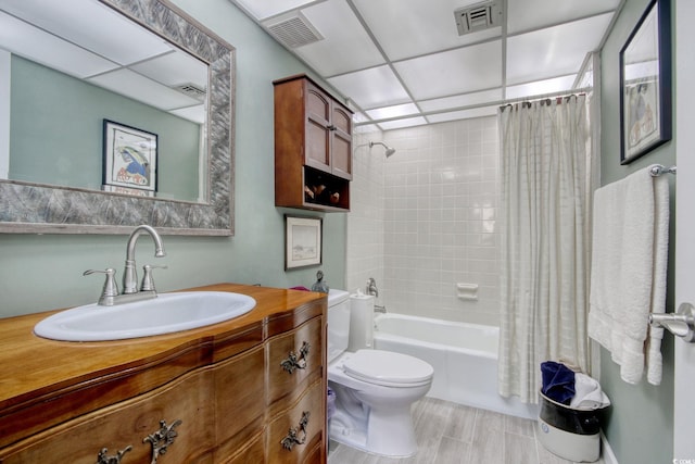 full bathroom featuring a paneled ceiling, vanity, toilet, and shower / tub combo with curtain