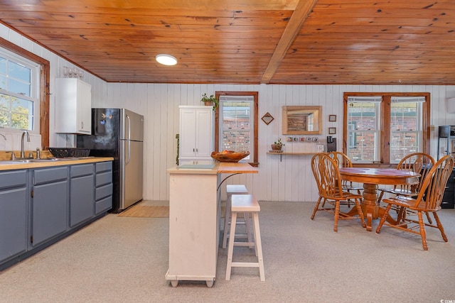 kitchen featuring sink, beamed ceiling, white cabinets, gray cabinets, and wood walls