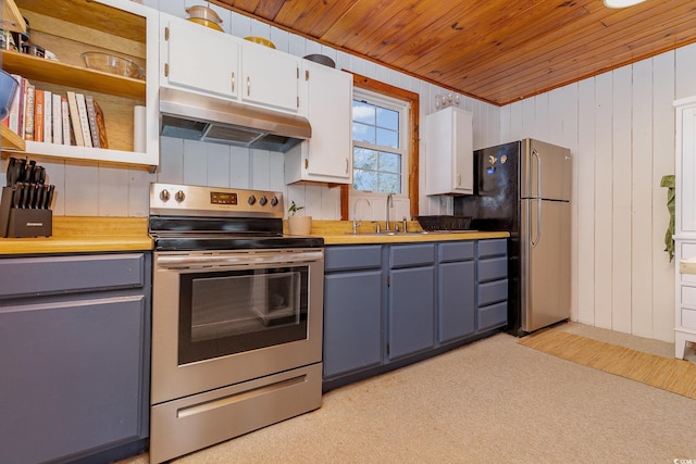 kitchen featuring appliances with stainless steel finishes, light colored carpet, wooden walls, sink, and white cabinetry