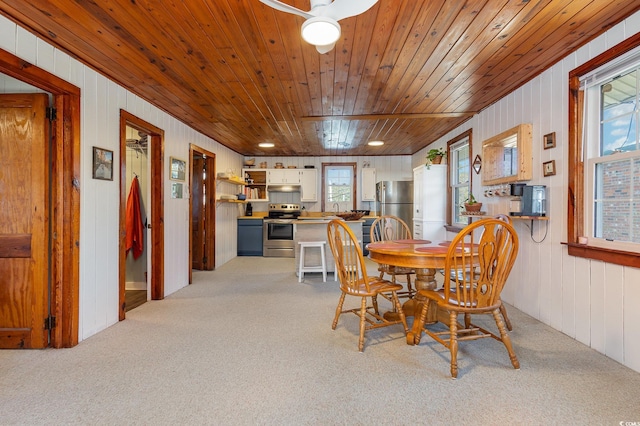 carpeted dining space with wooden walls, ceiling fan, and wood ceiling