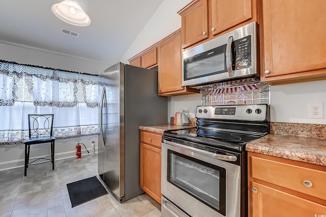 kitchen with stainless steel appliances, light tile patterned flooring, and lofted ceiling