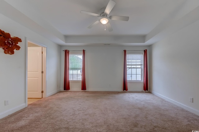 unfurnished room featuring ceiling fan, a tray ceiling, and plenty of natural light