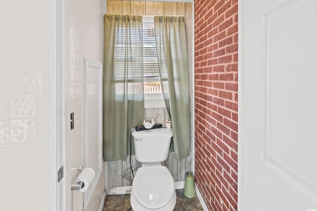 bathroom with brick wall and toilet