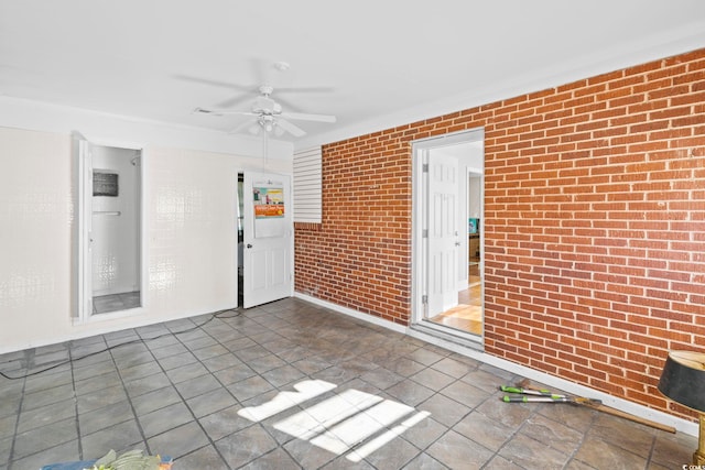 unfurnished room featuring ceiling fan and brick wall