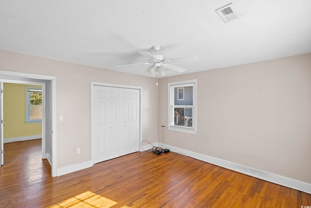 unfurnished bedroom with ceiling fan, a closet, and hardwood / wood-style flooring