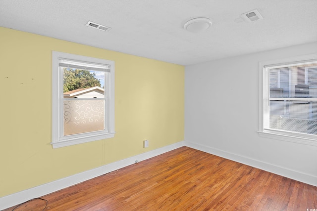 empty room with wood-type flooring and a textured ceiling