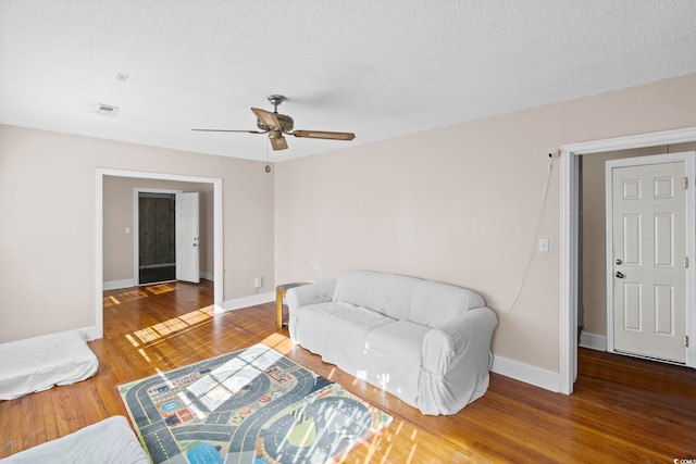 living room featuring a textured ceiling, hardwood / wood-style flooring, and ceiling fan