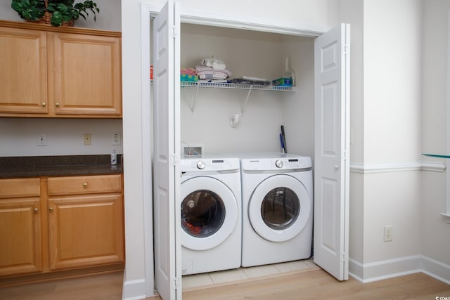 clothes washing area with washer and clothes dryer and light hardwood / wood-style floors