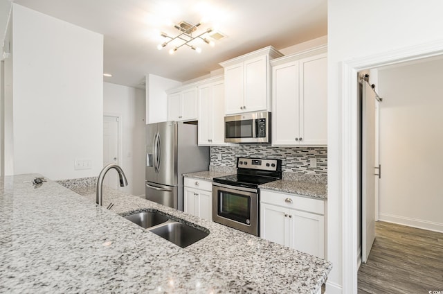 kitchen with sink, appliances with stainless steel finishes, white cabinetry, light stone countertops, and decorative backsplash