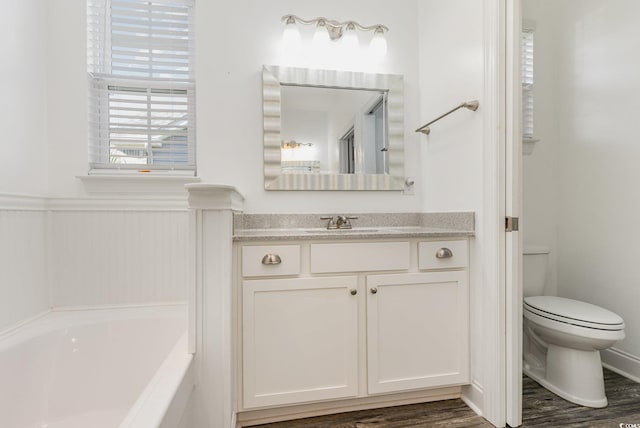 bathroom with vanity, hardwood / wood-style flooring, a tub, and toilet