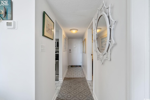 hall with light tile patterned floors and a textured ceiling