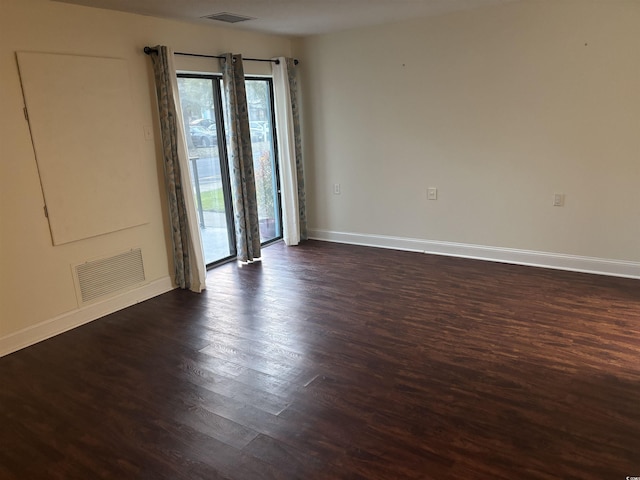 unfurnished room featuring baseboards, visible vents, and dark wood-type flooring