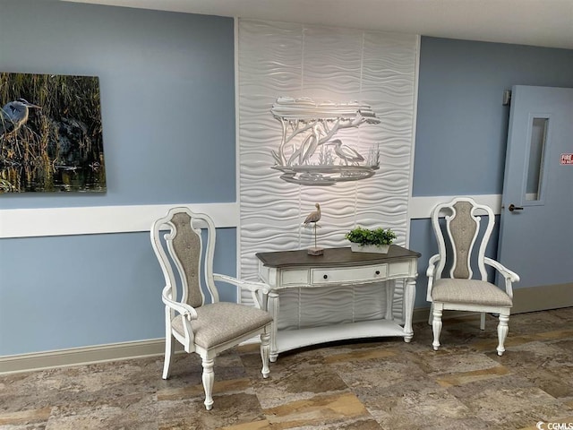 living area featuring stone finish flooring and baseboards