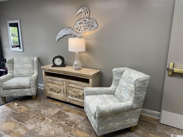 sitting room with stone finish flooring and baseboards