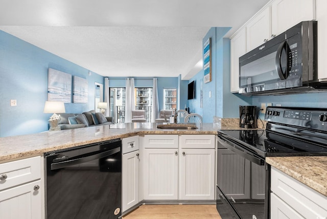 kitchen featuring black appliances, white cabinets, sink, light stone countertops, and light wood-type flooring