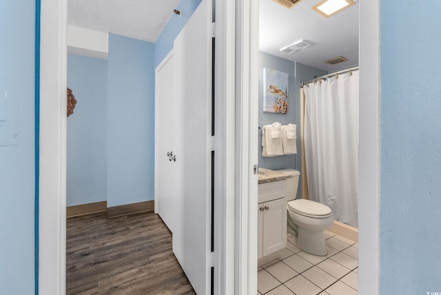 bathroom with a shower with curtain, vanity, a textured ceiling, and toilet