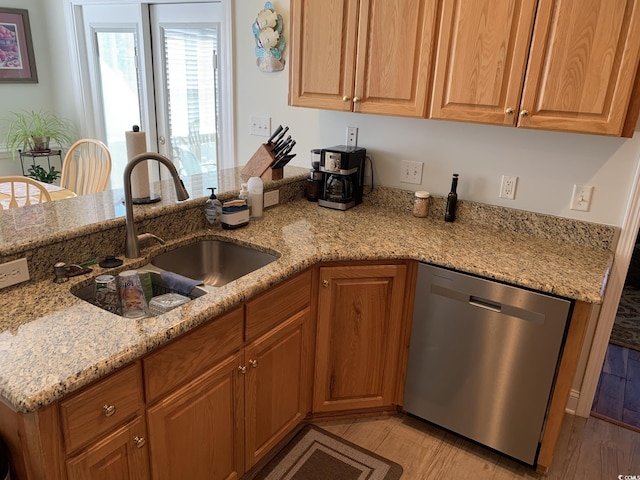 kitchen featuring stainless steel dishwasher, light stone countertops, sink, and light hardwood / wood-style flooring