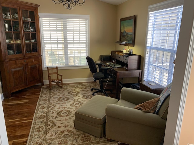 home office with dark hardwood / wood-style flooring and an inviting chandelier