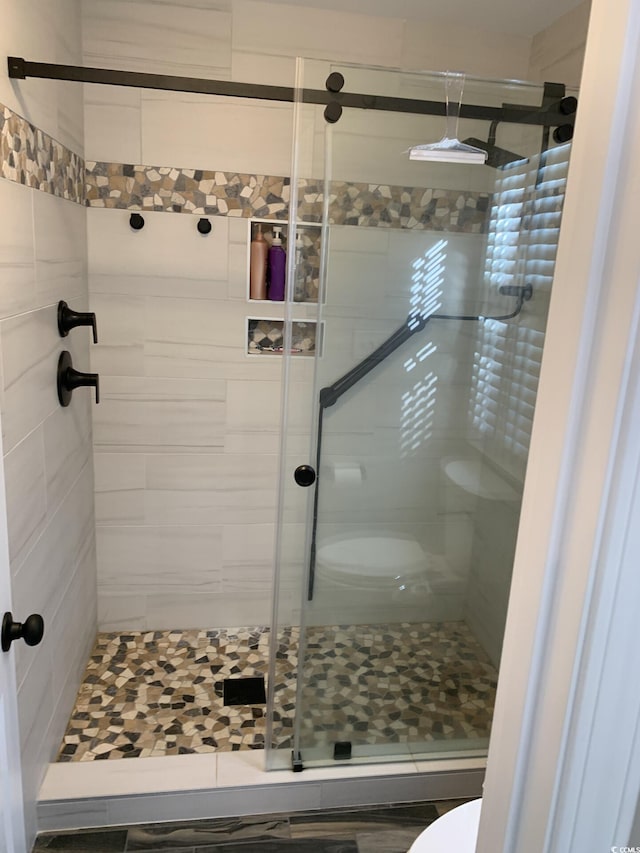 bathroom with toilet and a shower with shower door