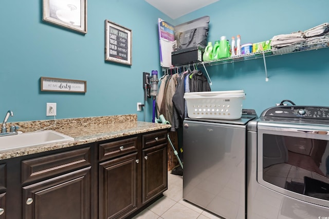 laundry area with cabinets, light tile patterned floors, washer and clothes dryer, and sink