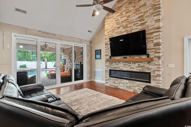 living room with a fireplace, hardwood / wood-style flooring, high vaulted ceiling, and ceiling fan