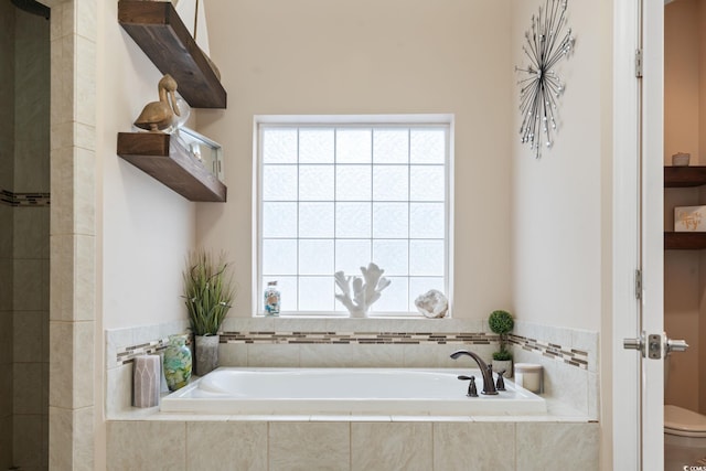 bathroom with a relaxing tiled tub and toilet