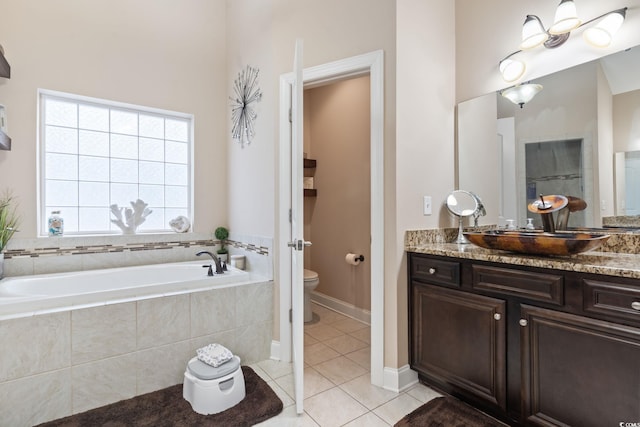 bathroom with tile patterned floors, tiled bath, vanity, and toilet