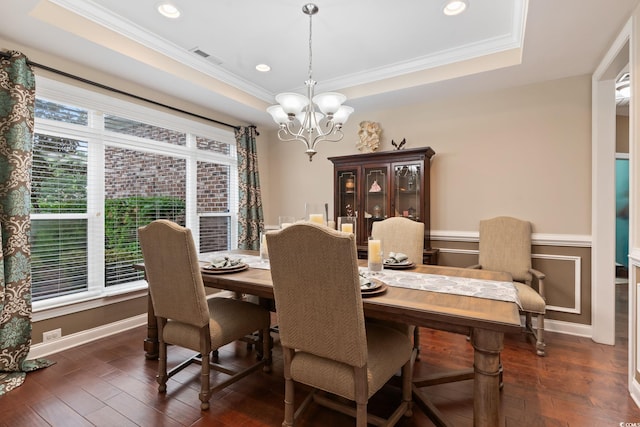 dining space with a notable chandelier, a raised ceiling, ornamental molding, and dark wood-type flooring