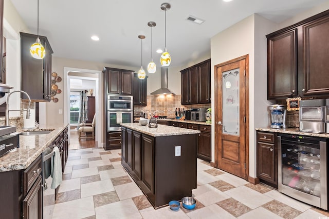 kitchen with pendant lighting, a center island, wall chimney range hood, and wine cooler