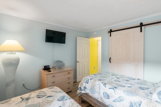 bedroom featuring a barn door, crown molding, and wood-type flooring