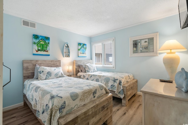 bedroom with a textured ceiling, crown molding, and wood-type flooring