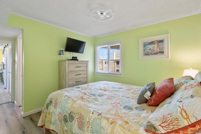 bedroom featuring a textured ceiling, ornamental molding, and light hardwood / wood-style flooring