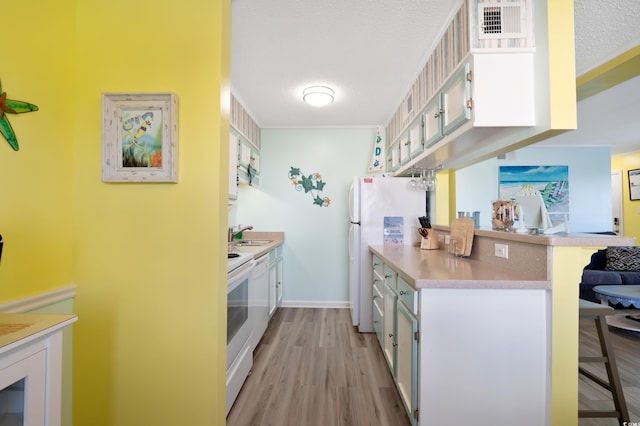 kitchen with a kitchen breakfast bar, white cabinetry, and range