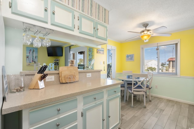 kitchen with crown molding, ceiling fan, light stone counters, a textured ceiling, and light hardwood / wood-style flooring