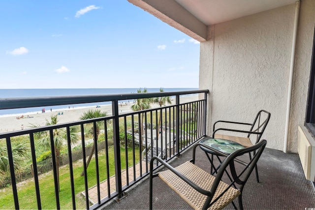 balcony with a water view and a view of the beach