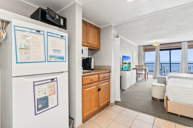 kitchen with fridge, crown molding, and light tile patterned flooring