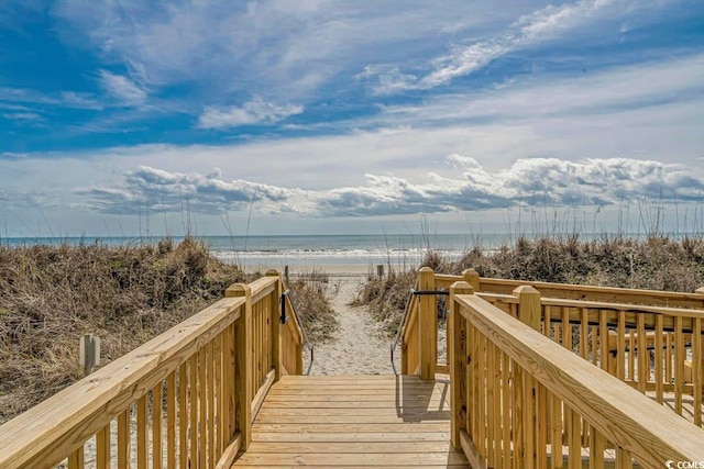 view of community with a deck with water view and a view of the beach