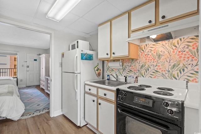 501 S Ocean Blvd Unit 708, North Myrtle Beach, SC 29582 - kitchen with black electric range oven, under cabinet range hood, a sink, freestanding refrigerator, and light wood-style floors