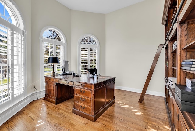 office area featuring a towering ceiling and light wood-type flooring