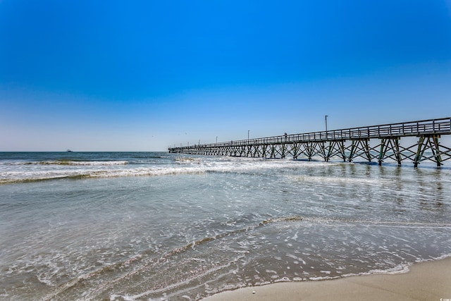 view of dock featuring a beach view and a water view