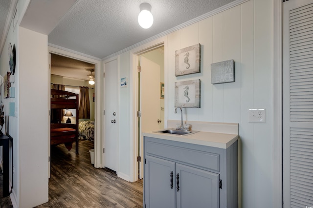 bathroom with ceiling fan, crown molding, a textured ceiling, vanity, and hardwood / wood-style flooring