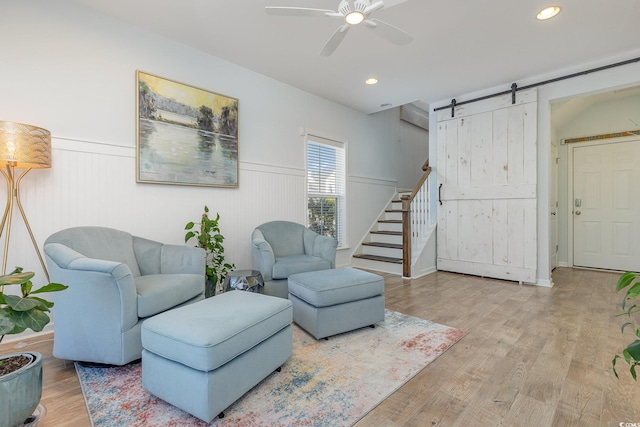 living room featuring a barn door, ceiling fan, and light wood-type flooring