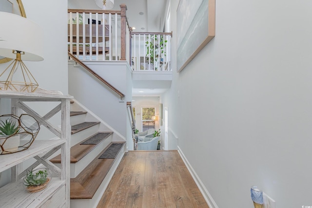 stairs featuring wood-type flooring and a high ceiling