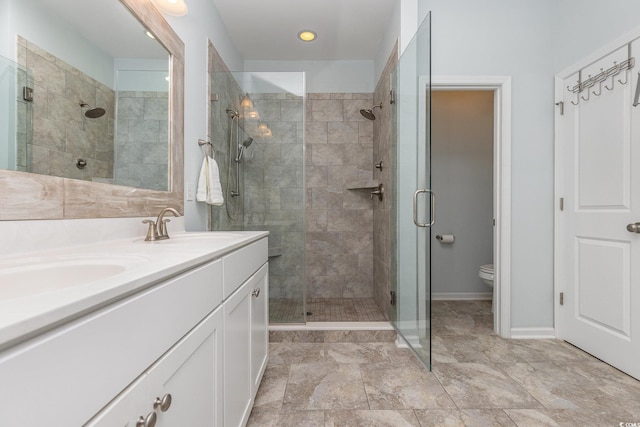 bathroom featuring a shower with door, vanity, and toilet