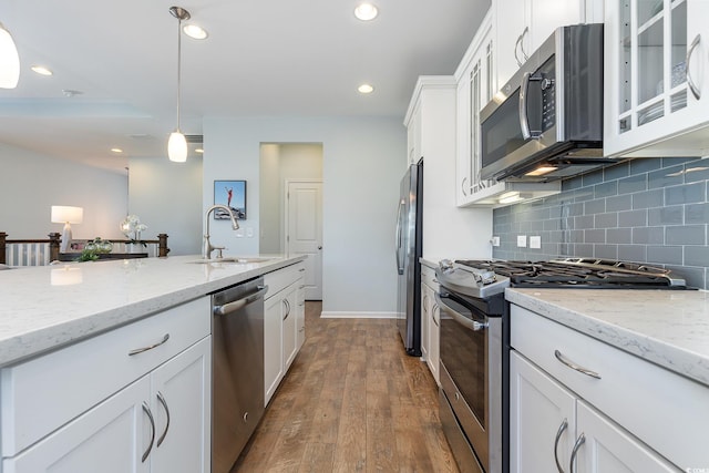 kitchen with white cabinets, hanging light fixtures, sink, appliances with stainless steel finishes, and dark hardwood / wood-style flooring